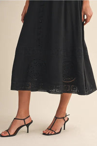 Black embroidered lace sleeveless empire midi dress with delicate circular cutout patterns along the hem