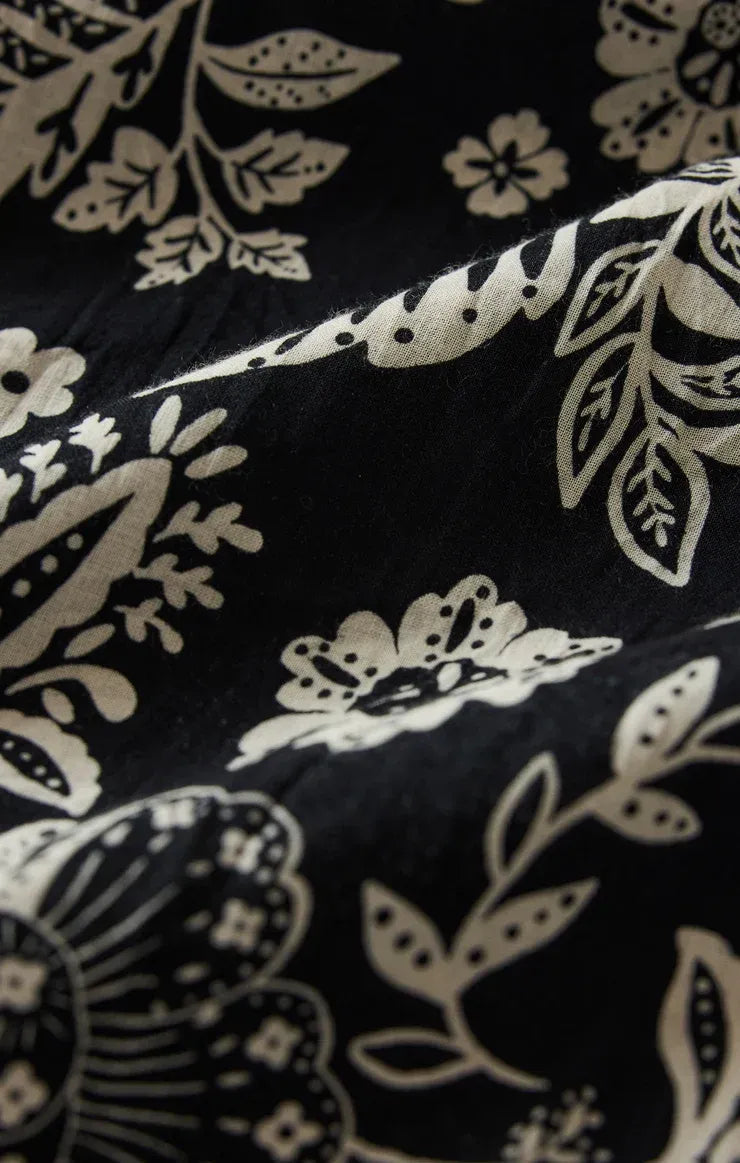Black fabric with intricate cream floral and leaf patterns on halter viento luz floral midi dress