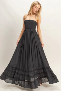 Black halter neck maxi dress featuring a ribbed smocked bodice and a flowing tiered hem skirt
