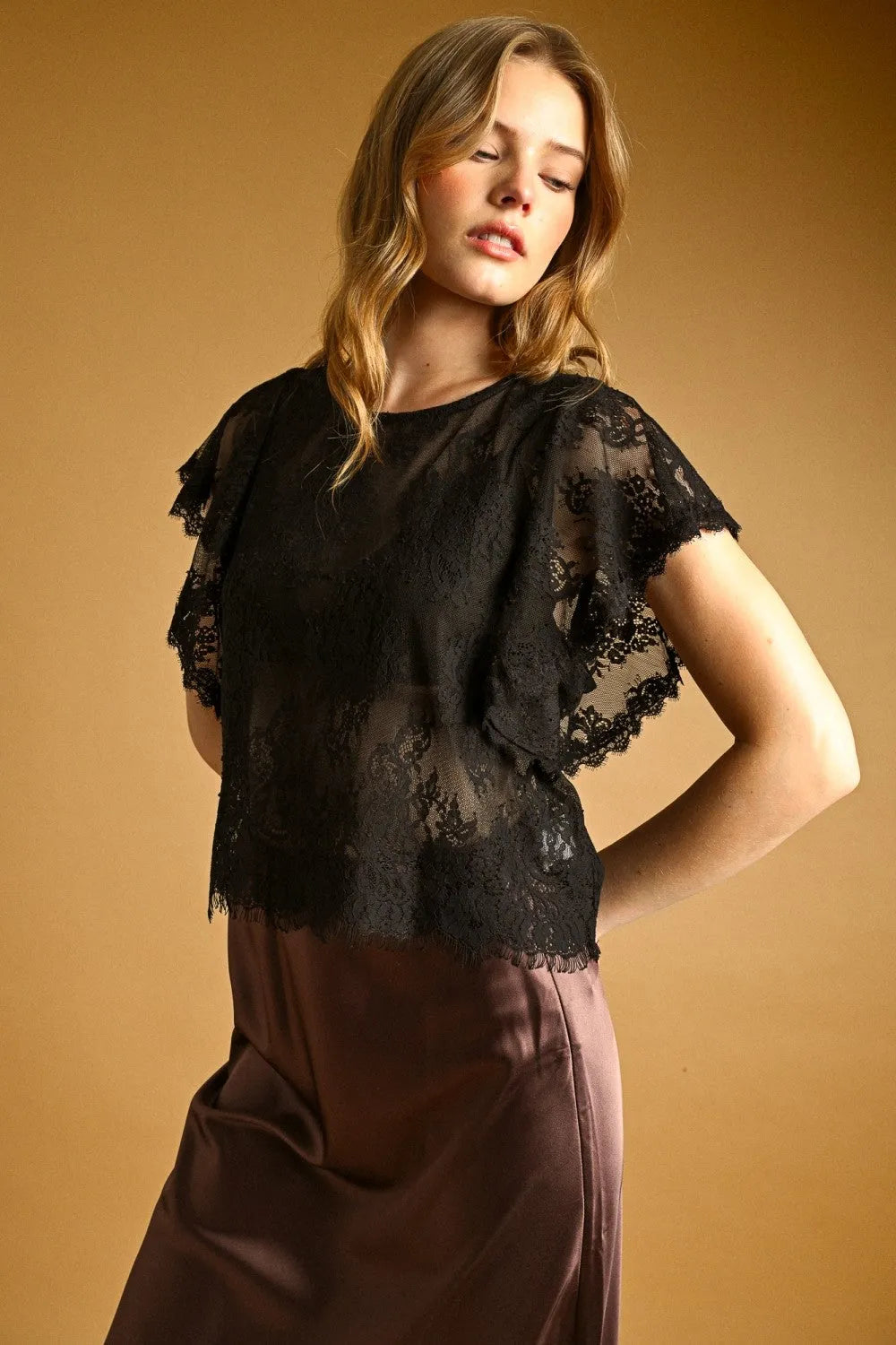 Black lace scalloped blouse featuring ruffled short sleeves and a sheer overlay for elegant wear