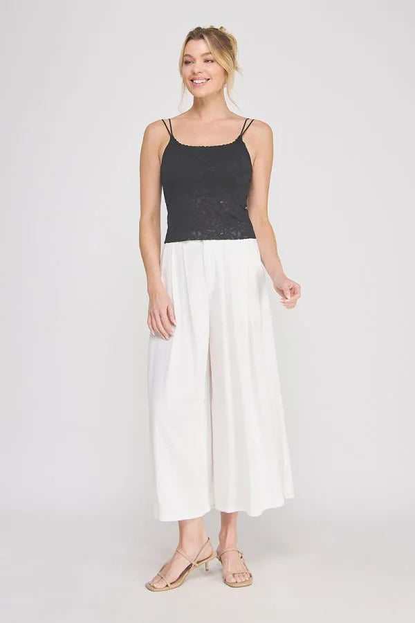 Black lace-trimmed padded floral laced bralette with spaghetti straps paired with white wide-leg pants
