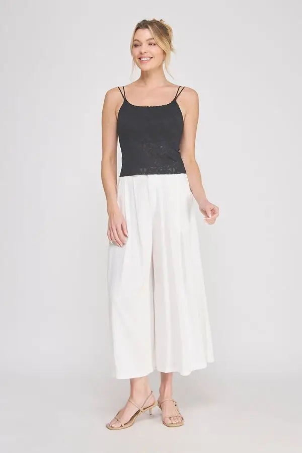 Black lace-trimmed padded floral laced bralette with spaghetti straps paired with white wide-leg pants