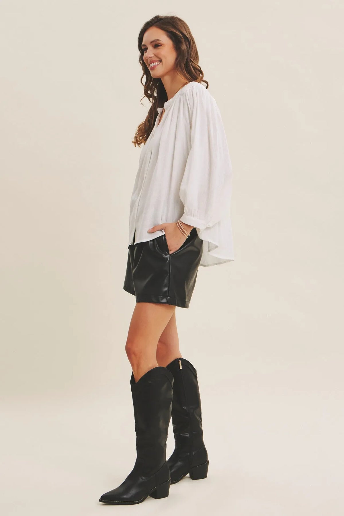 Black leather knee-high boots with block heel and cowboy design paired with espresso hour linen blend blouse