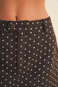 Black linen polka dot utility skort featuring white dots and a brown button closure for stylish wear
