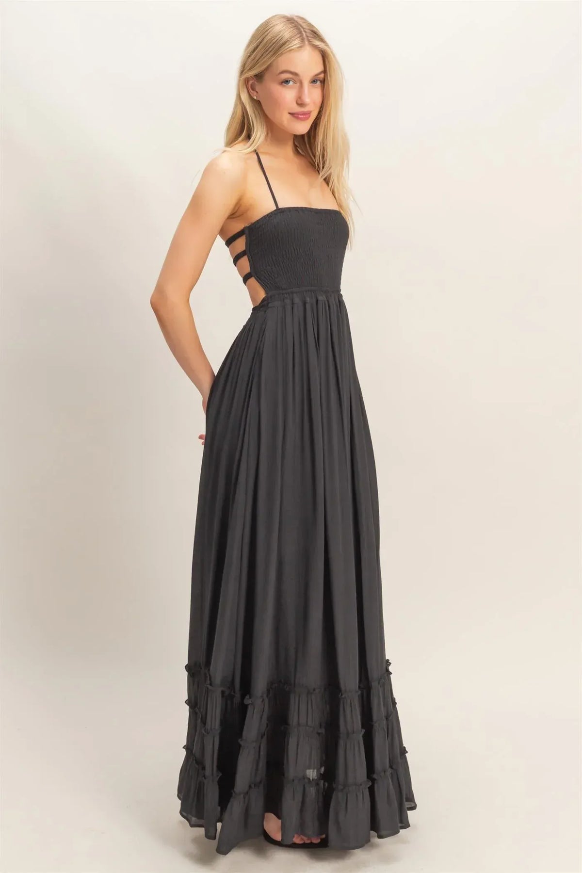Black maxi dress with smocked bodice, thin straps, crisscross back, and tiered hem ruffles shown from the back