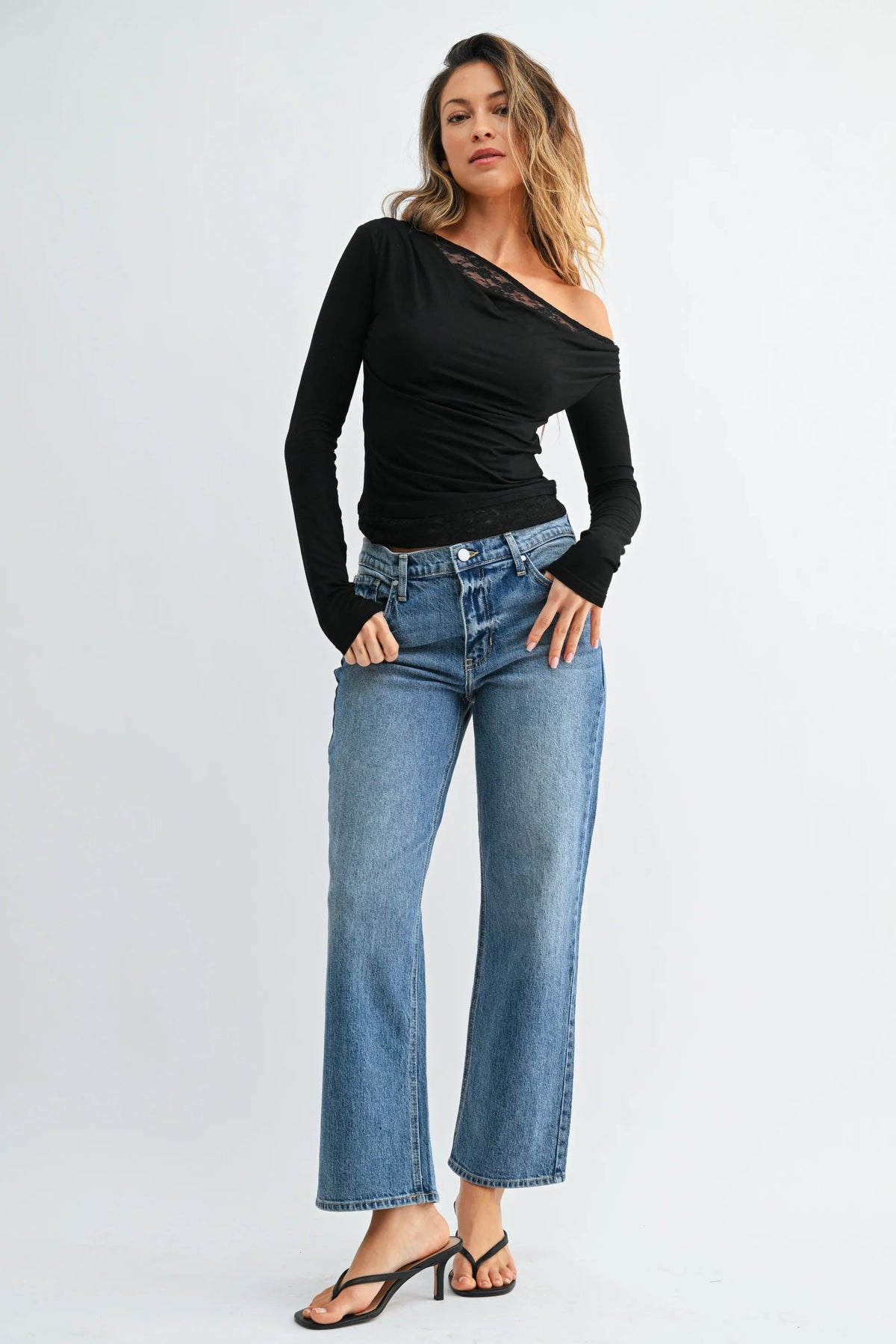 Black one-shoulder long-sleeve top with lace trim paired with mid rise classic straight leg jeans denim
