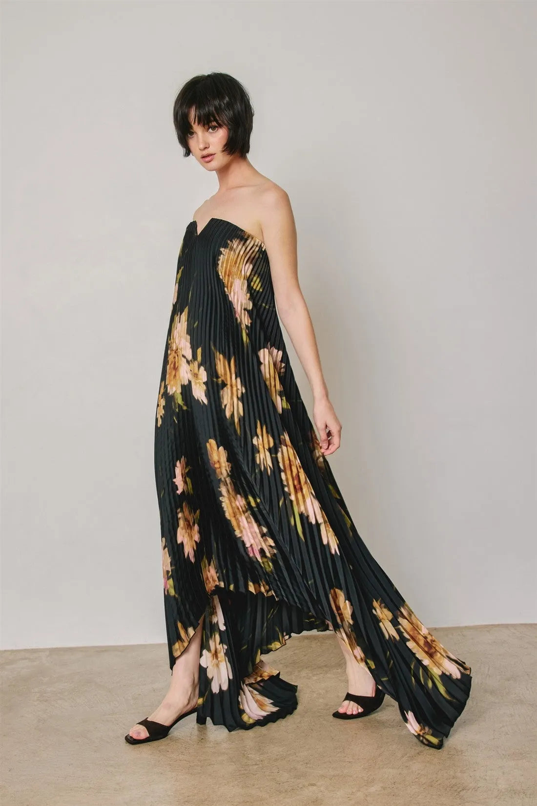 Black floral strapless pleated maxi column dress with gold and peach floral pattern in lightweight fabric