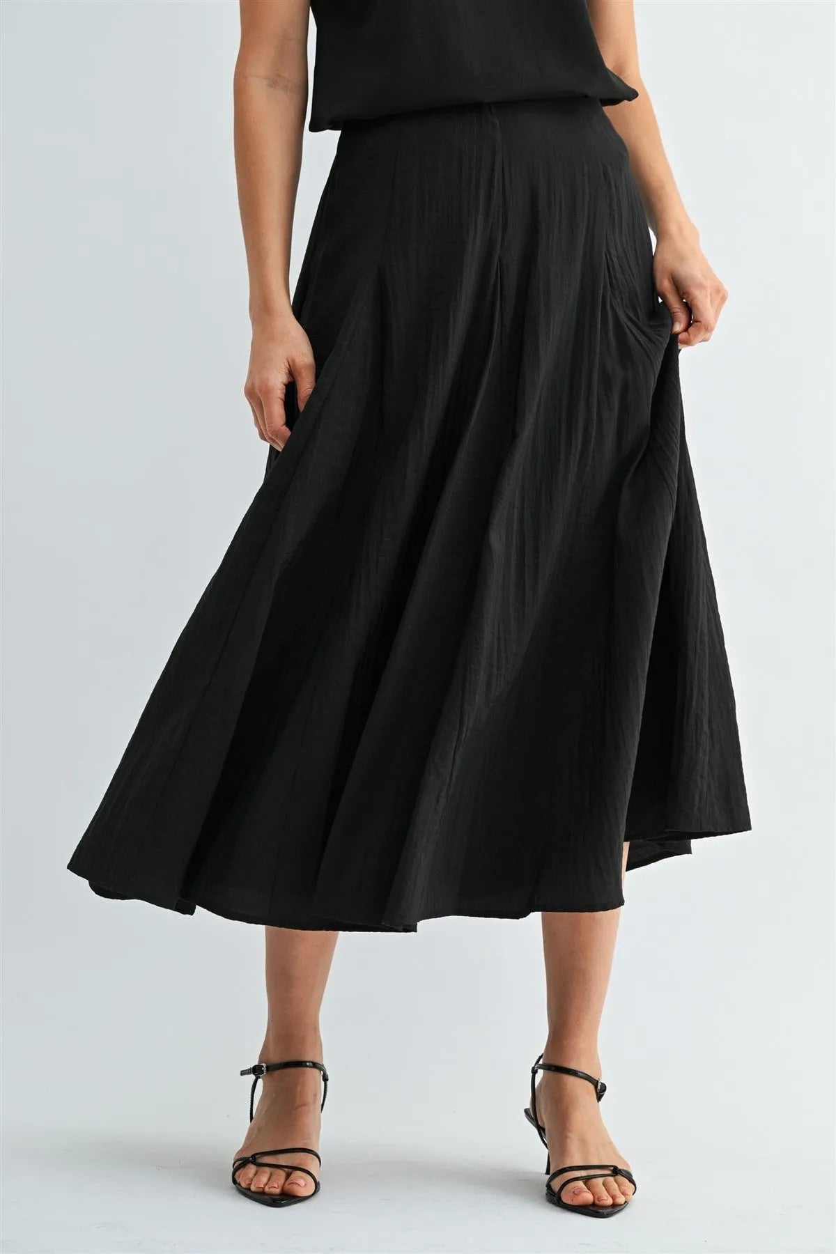 Black godet midi skirt with pleats and flowing asymmetrical hemline featuring a side zipper closure