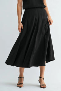 Black godet midi skirt with pleats and flowing asymmetrical hemline featuring a side zipper closure