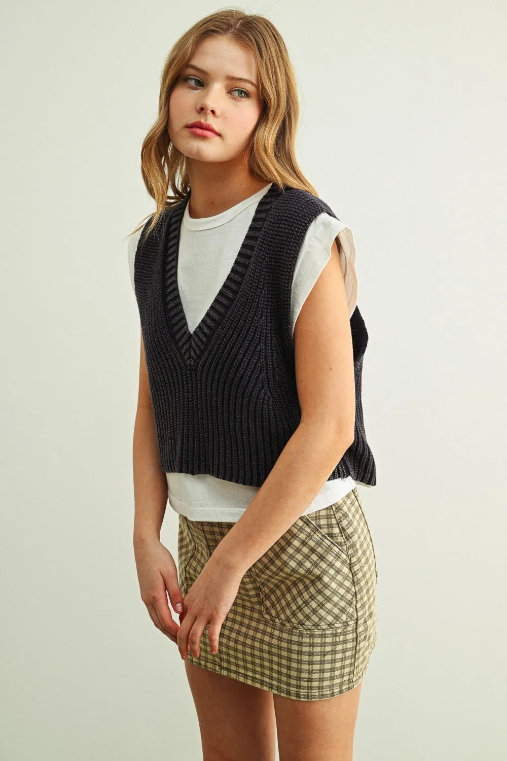 Black ribbed knit v-neck sweater vest worn over white jersey top showcasing sweater vest with jersey top combo product