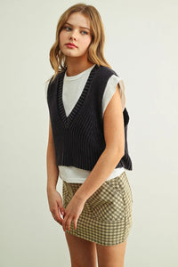 Black ribbed knit v-neck sweater vest worn over white jersey top showcasing sweater vest with jersey top combo product
