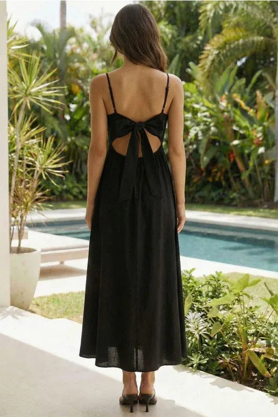 Black satin sleeveless tie flared midi dress with thin spaghetti straps and back bow detail shown from the back