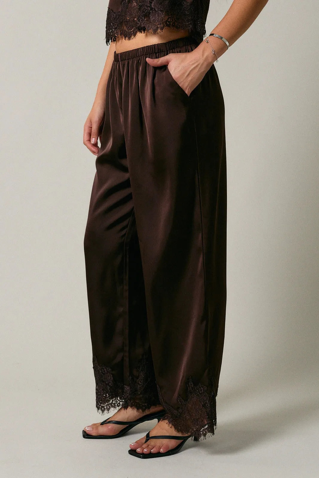 Black satin elastic waist lace trim wide leg pants featuring delicate lace trim at the hem for elegant style