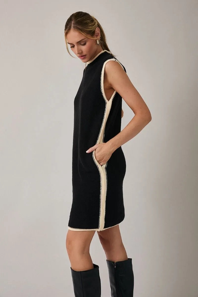 Black mock neck sleeveless sweater dress with cream trim along sides and neckline in knit fabric