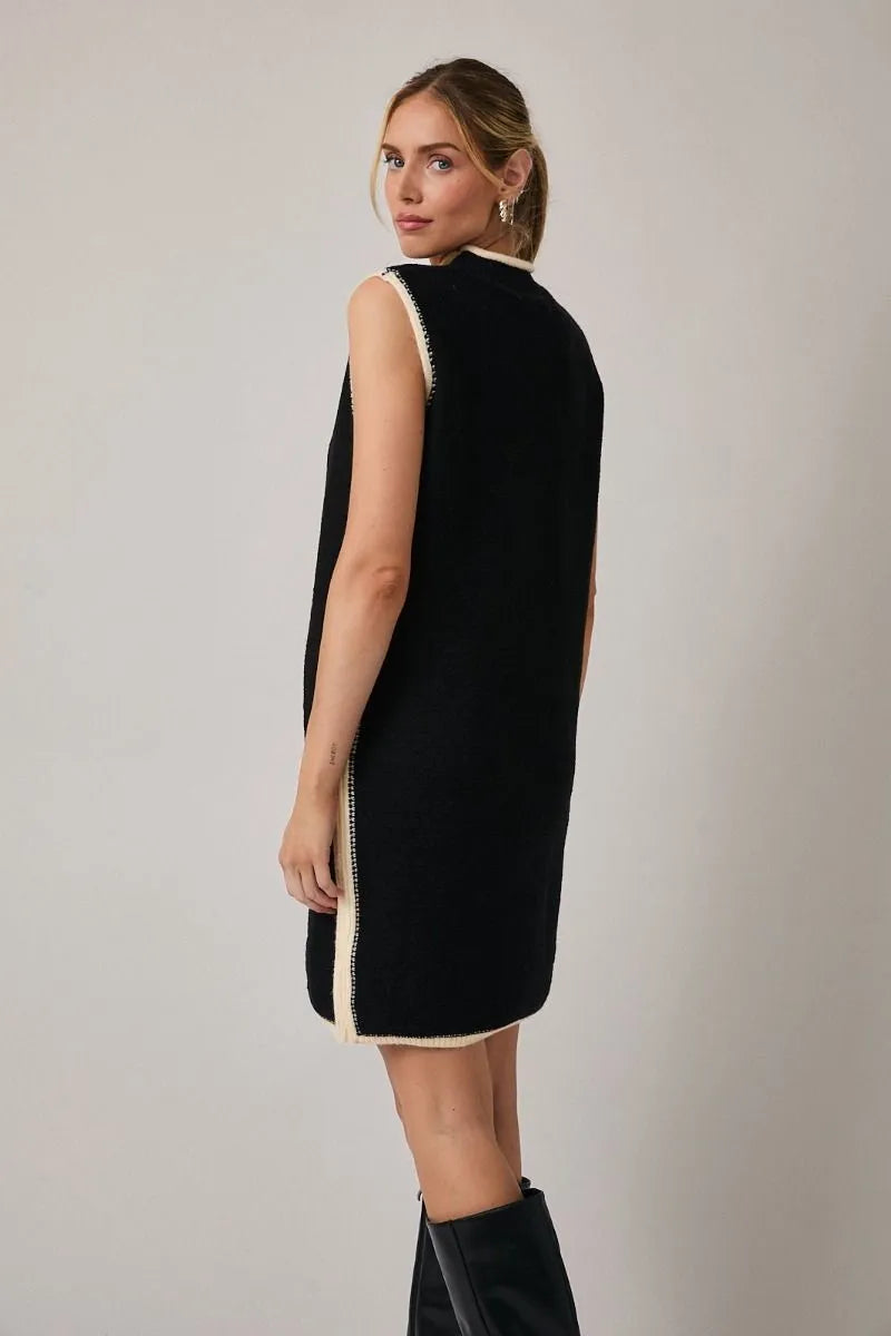 Black sleeveless knit sweater dress with cream trim features a mock neck and elegant sleeveless design