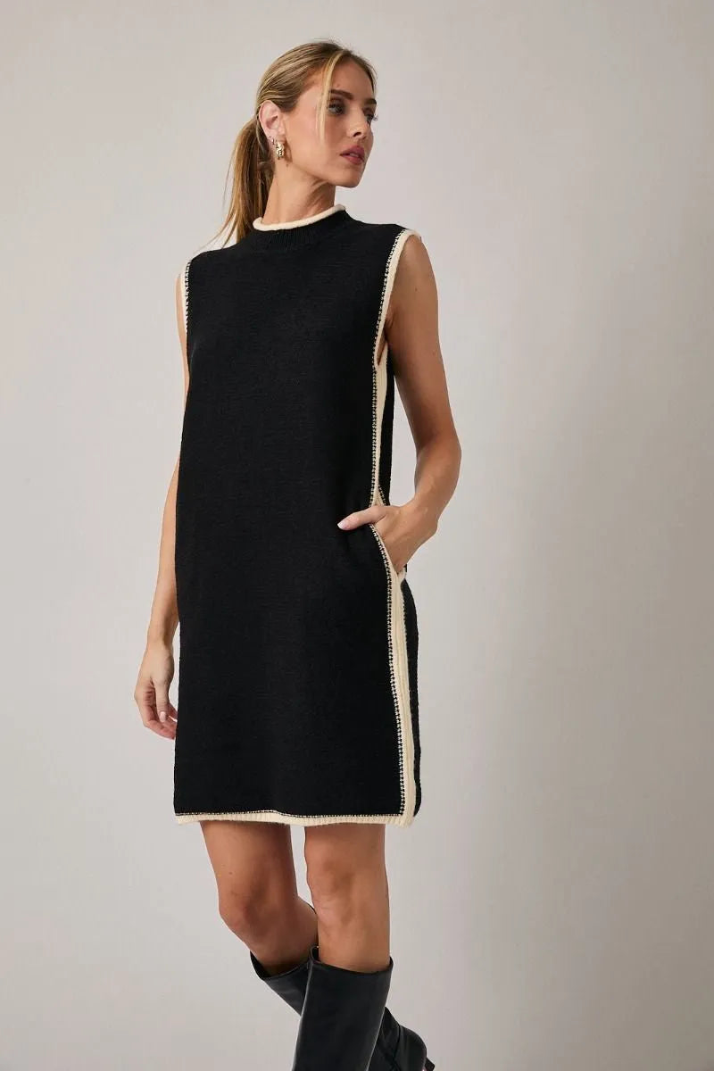 Black sleeveless knit mock neck sweater dress with cream trim along neckline side seams and hem