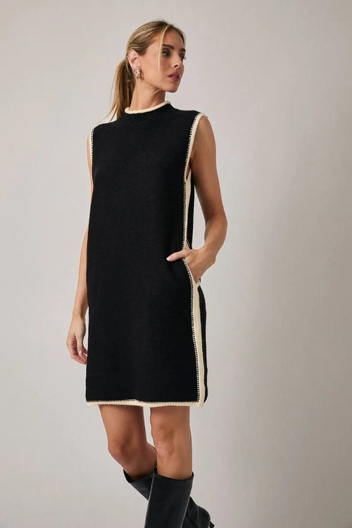 Black sleeveless knit mock neck sweater dress with cream trim along neckline side seams and hem
