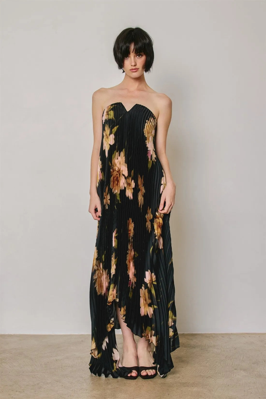 Black floral strapless pleated maxi column dress with peach and brown bold floral pattern and asymmetrical hem
