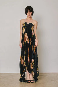 Black floral strapless pleated maxi column dress with peach and brown bold floral pattern and asymmetrical hem