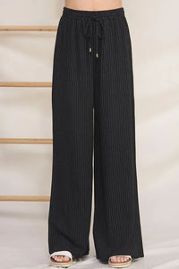 Black wide-leg striped linen smock pants with thin white vertical stripes and elastic drawstring smock waist