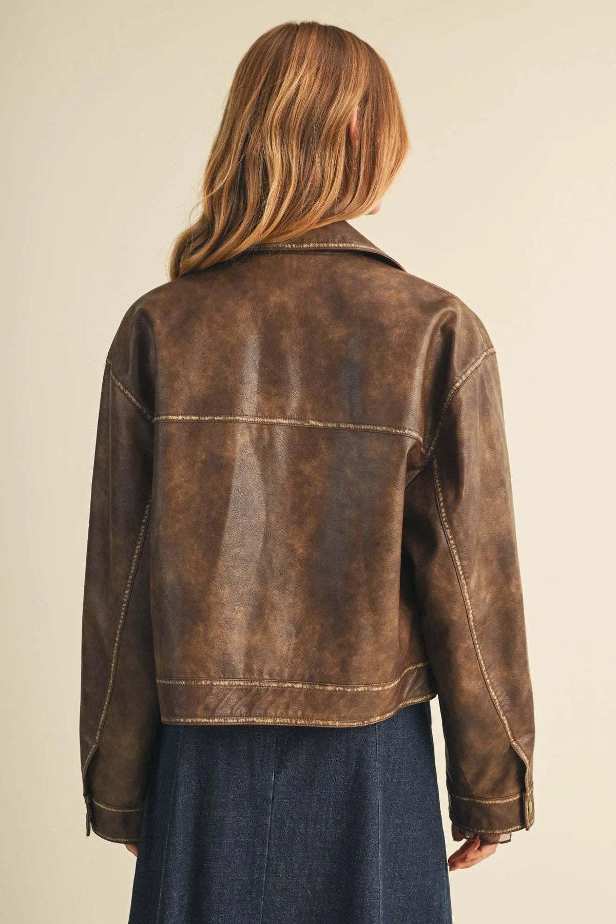 Brown distressed faux leather moto jacket with contrasting light stitching in coated knit boxy utility style