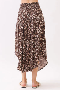 A flowing brown floral midi skirt with a high-waisted smocked waistband and asymmetrical hemline