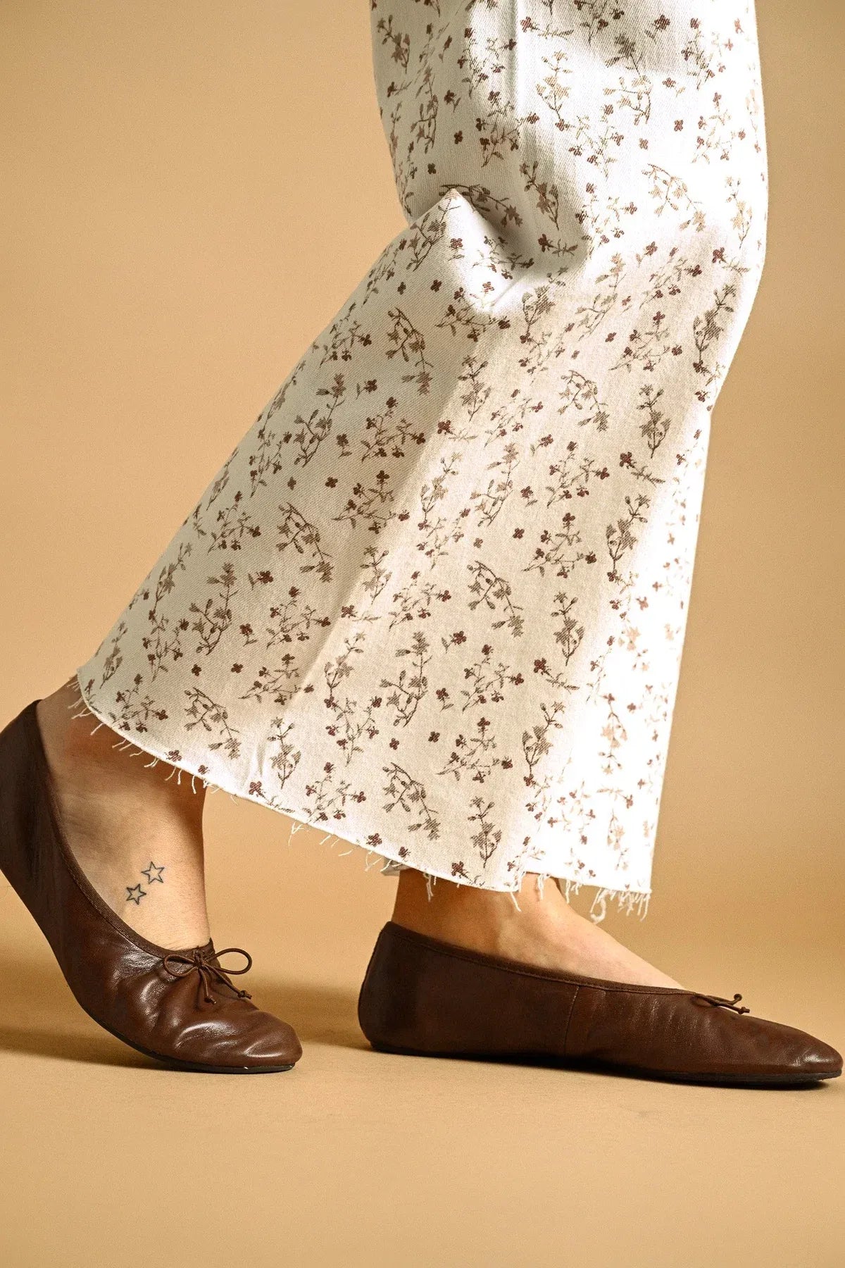 Brown leather ballet flats with a delicate bow paired with floral print stretched wide leg pants for a stylish look