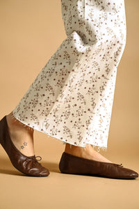 Brown leather ballet flats with a delicate bow paired with floral print stretched wide leg pants for a stylish look