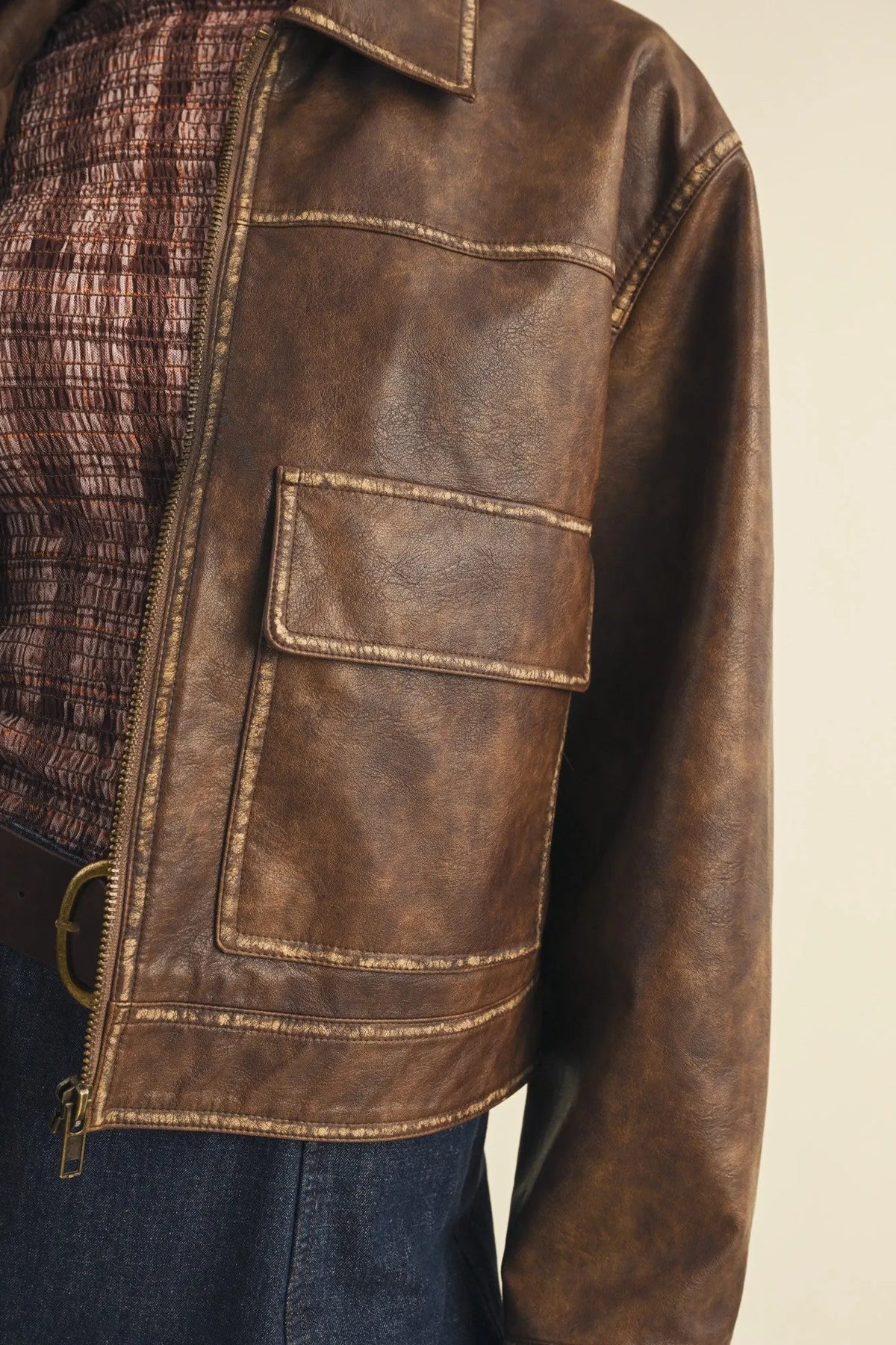 Brown leather coated knit boxy utility jacket with textured distressed finish and gold toned stitching along seams