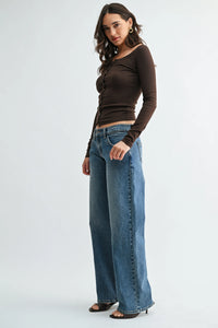Brown long-sleeved top with front button closure paired with low rise relaxed straight denim jeans featuring side seam detailing