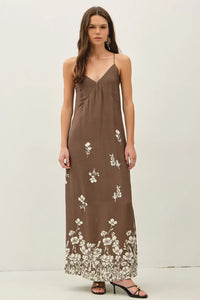 A flowing brown floral printed strappy tie maxi dress with delicate white floral embroidery along the hem and skirt