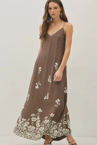 A flowing brown floral printed strappy tie maxi dress with white embroidery and thin spaghetti straps and v neckline