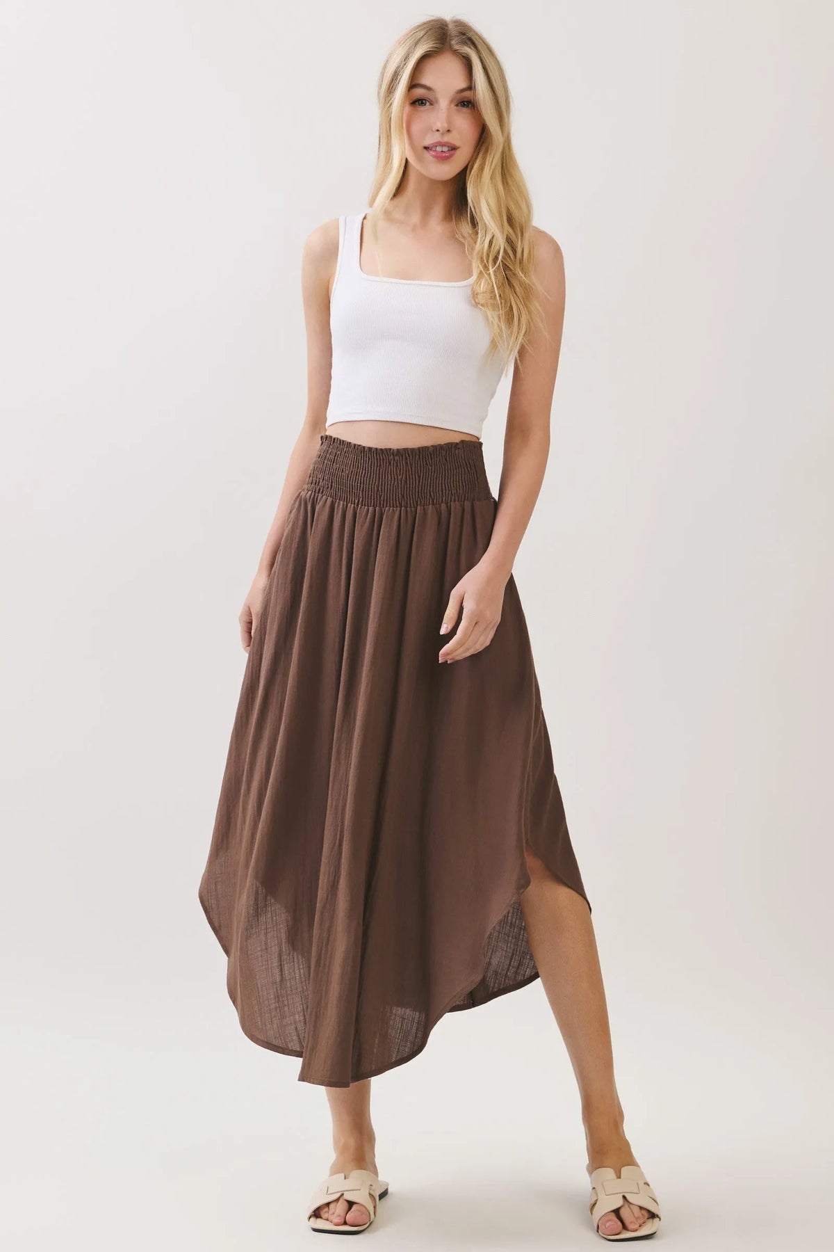 A flowing brown rounded hem midi skirt with smocked waistband lined and sheer side panels