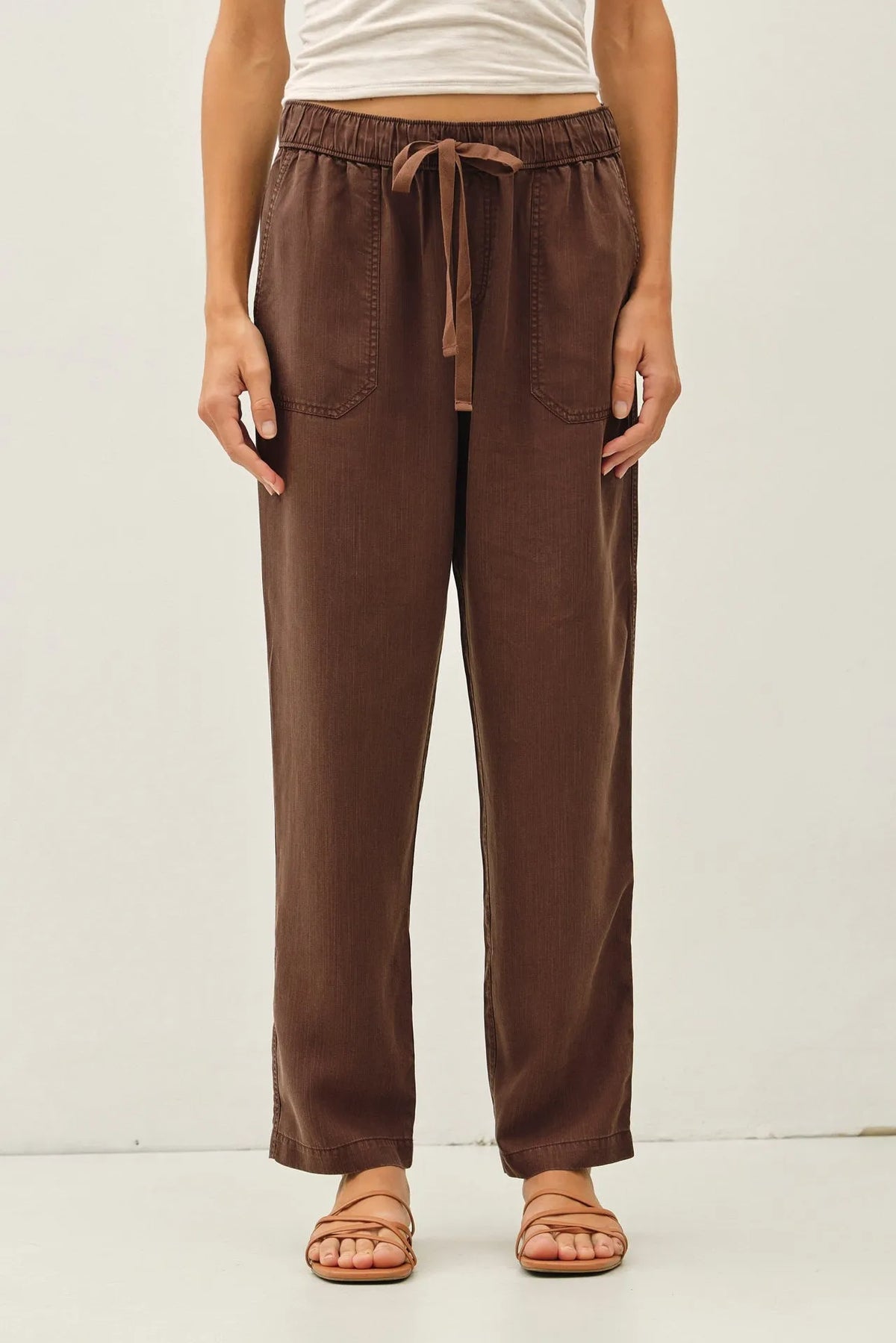 Brown tencel tapered pants with a relaxed fit and two front pockets made from soft breathable fabric