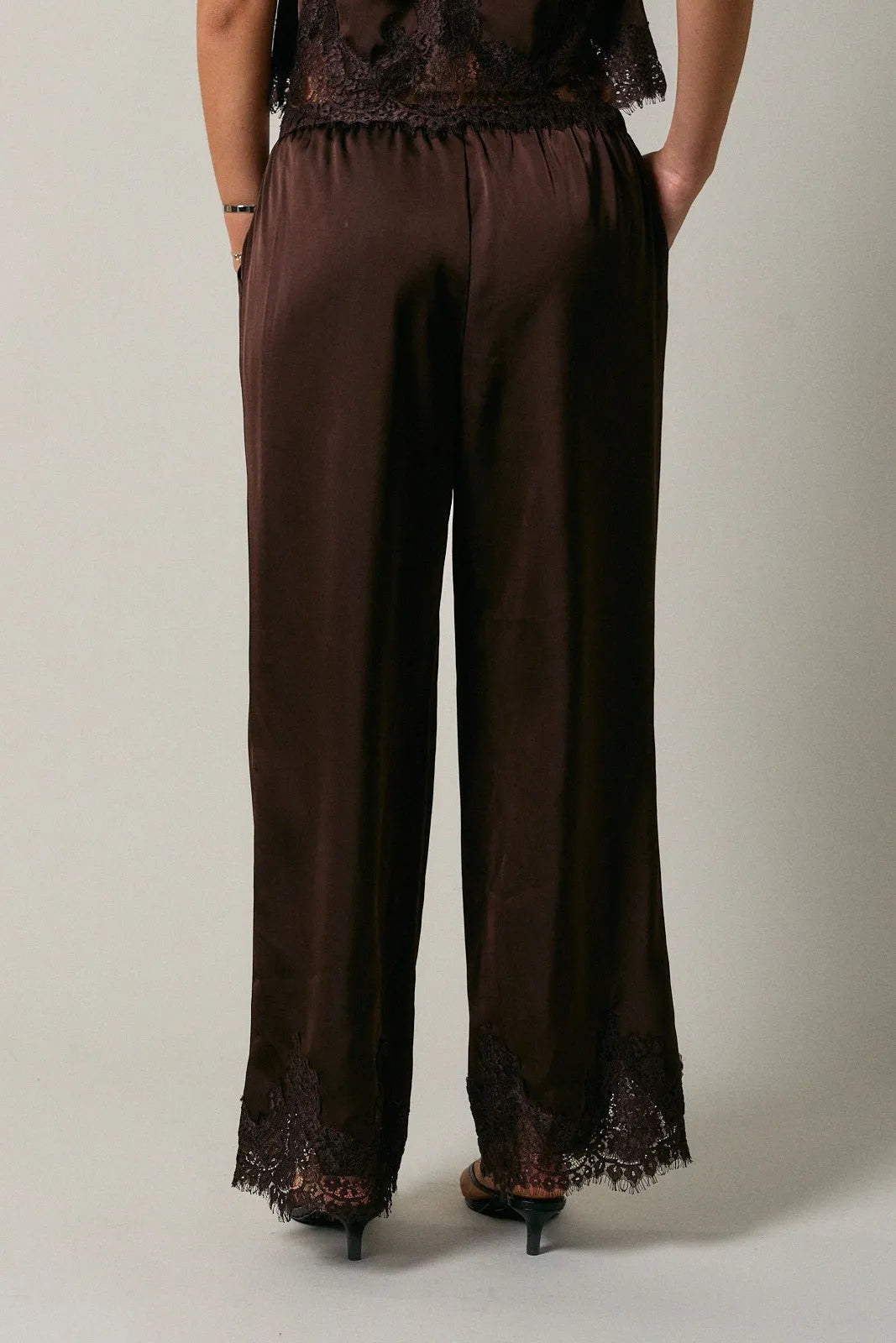 Brown satin wide-leg pants featuring elastic waist lace and black lace trim at waistband and hem