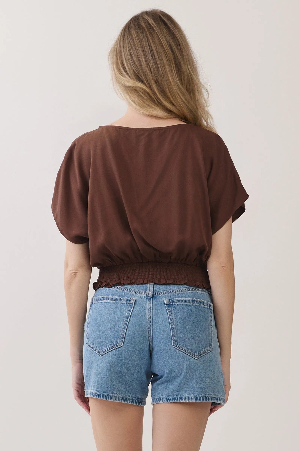 Brown short-sleeved neck button detailed blouse with gathered waistband and ruffled hem in lightweight fabric