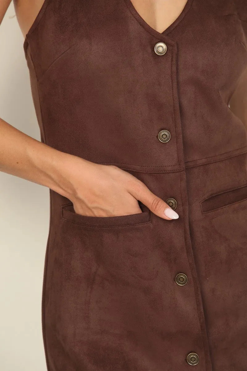 A brown suede halter neck mini dress with a v neckline, button front, and front pockets in suede material