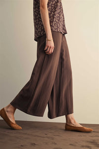 Brown wide leg pants with elastic waist and subtle vertical ribbed texture featuring side pockets