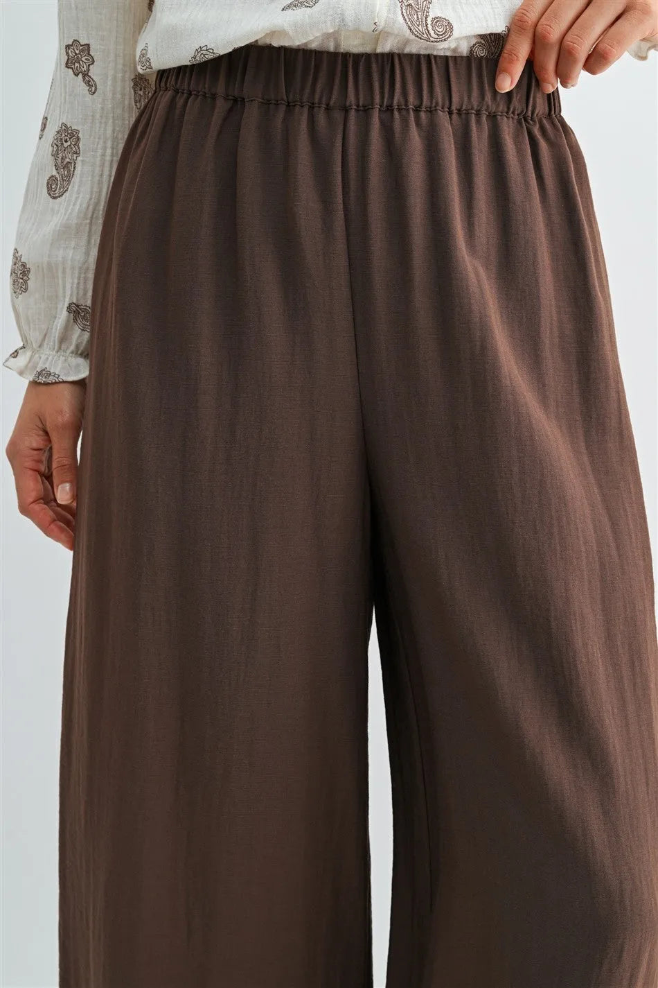 Brown wide leg pants with elastic waist and side pockets made from smooth flowing fabric