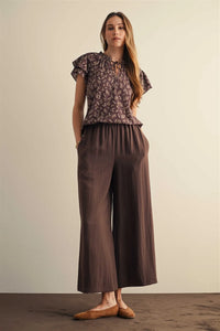Brown wide leg pants with elastic waist, side pockets, soft flowing fabric, and subtle vertical pleats