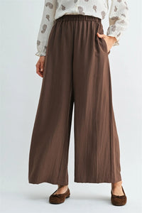 Brown wide leg pants with elastic waist side pockets made of soft flowing fabric for comfortable wear