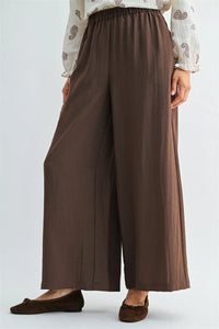 Brown wide leg pants with elastic waist and side pockets made of soft flowing fabric for comfortable wear