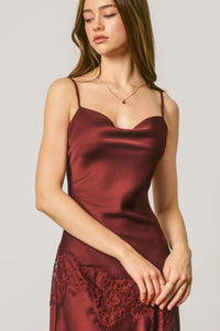 A burgundy satin midi slip dress featuring asymmetrical lace trim at the hem for elegant evening wear