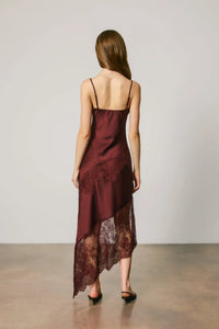 A burgundy satin slip dress featuring delicate asymmetrical lace trim along the hemline