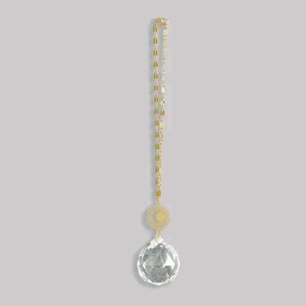 A clear faceted crystal pendant with gold-toned moon and sun charm on chain pocket suncatcher from shop daisy