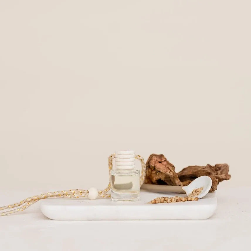 Clear glass car diffuser with white plastic cap and braided gold and white cord for luxury hanging fragrance use