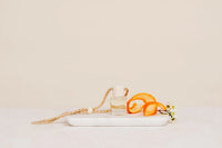 Hanging car diffuser with clear glass bottle, white ceramic cap, and woven rope strap for women’s boho chic clothing styles