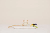 Clear glass car diffuser bottle with woven rope strap and white bead, featuring lavender and daisies for boho chic style