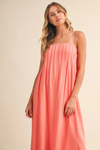 A flowing coral pintuck detailed strappy maxi dress with square neckline and vertical pleats