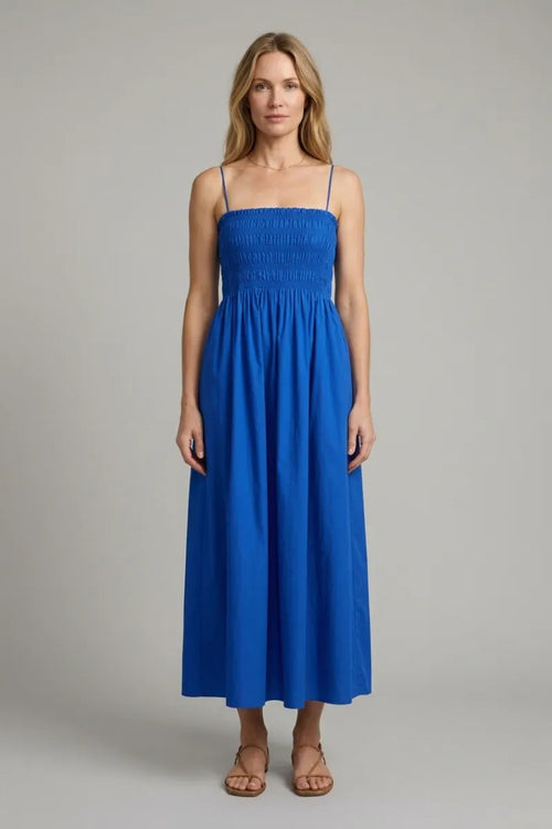 A vibrant royal blue cornelia poplin maxi dress with thin spaghetti straps and a smocked bodice in poplin fabric